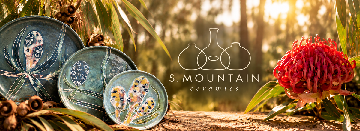 Golden woodland light with ceramic plates, S. Mountain Ceramics logo and a red waratah